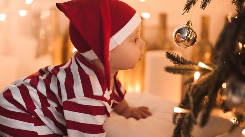 Crawling baby looking into Christmas bauble